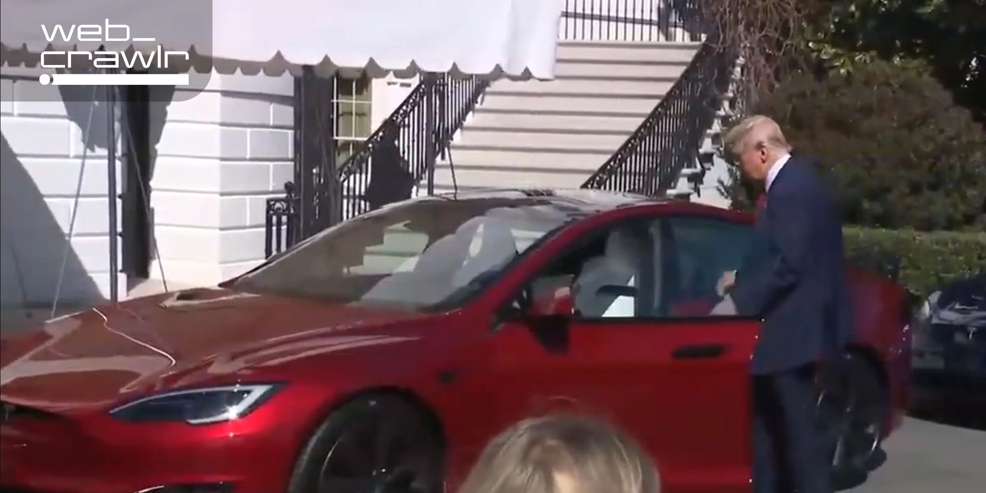 Trump walking into a Tesla. The Daily Dot newsletter web_crawlr logo is in the top left corner.