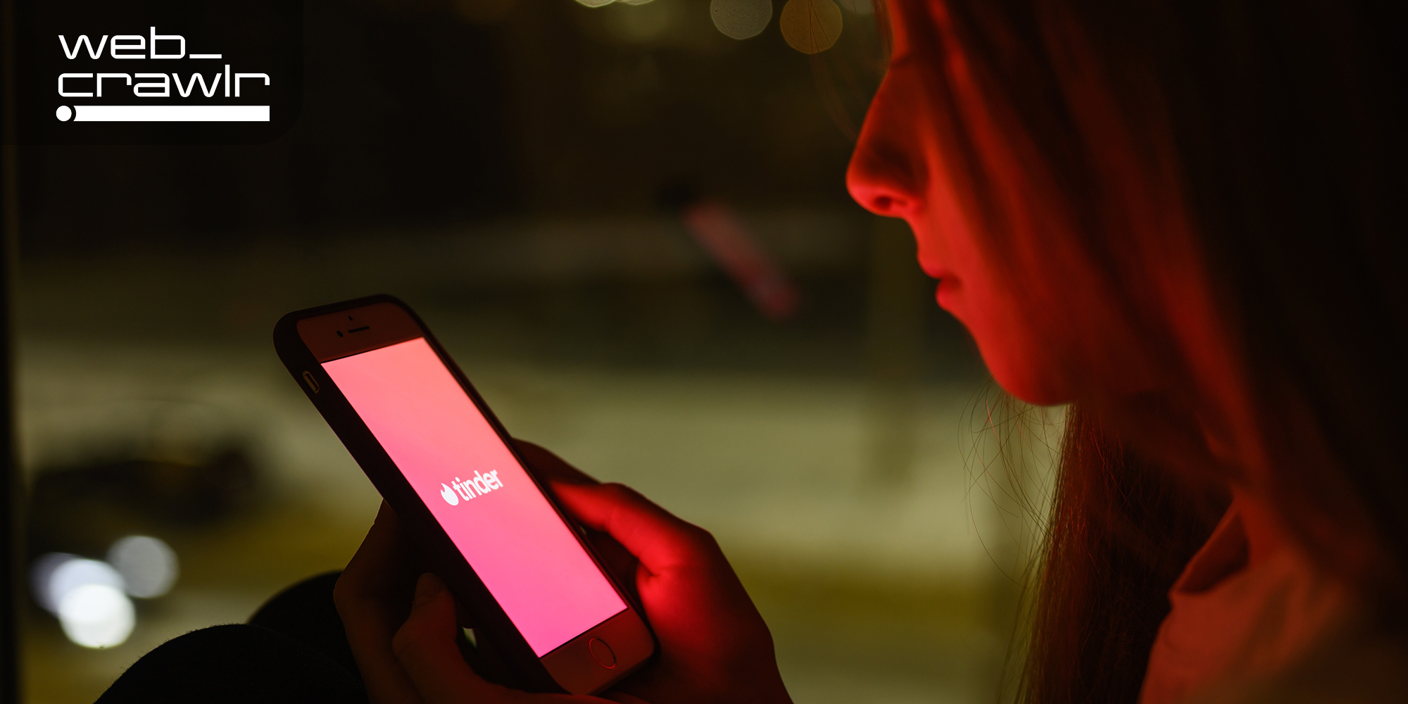 A person looking at Tinder on their phone. The Daily Dot newsletter web_crawlr logo is in the top left corner.