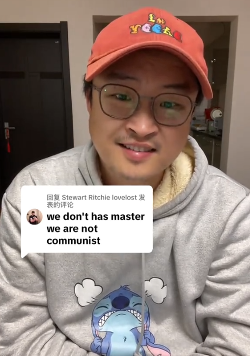 TikTok video of a man smiling at the camera as he replies to a comment reading 'we don't has master we are not communist.'