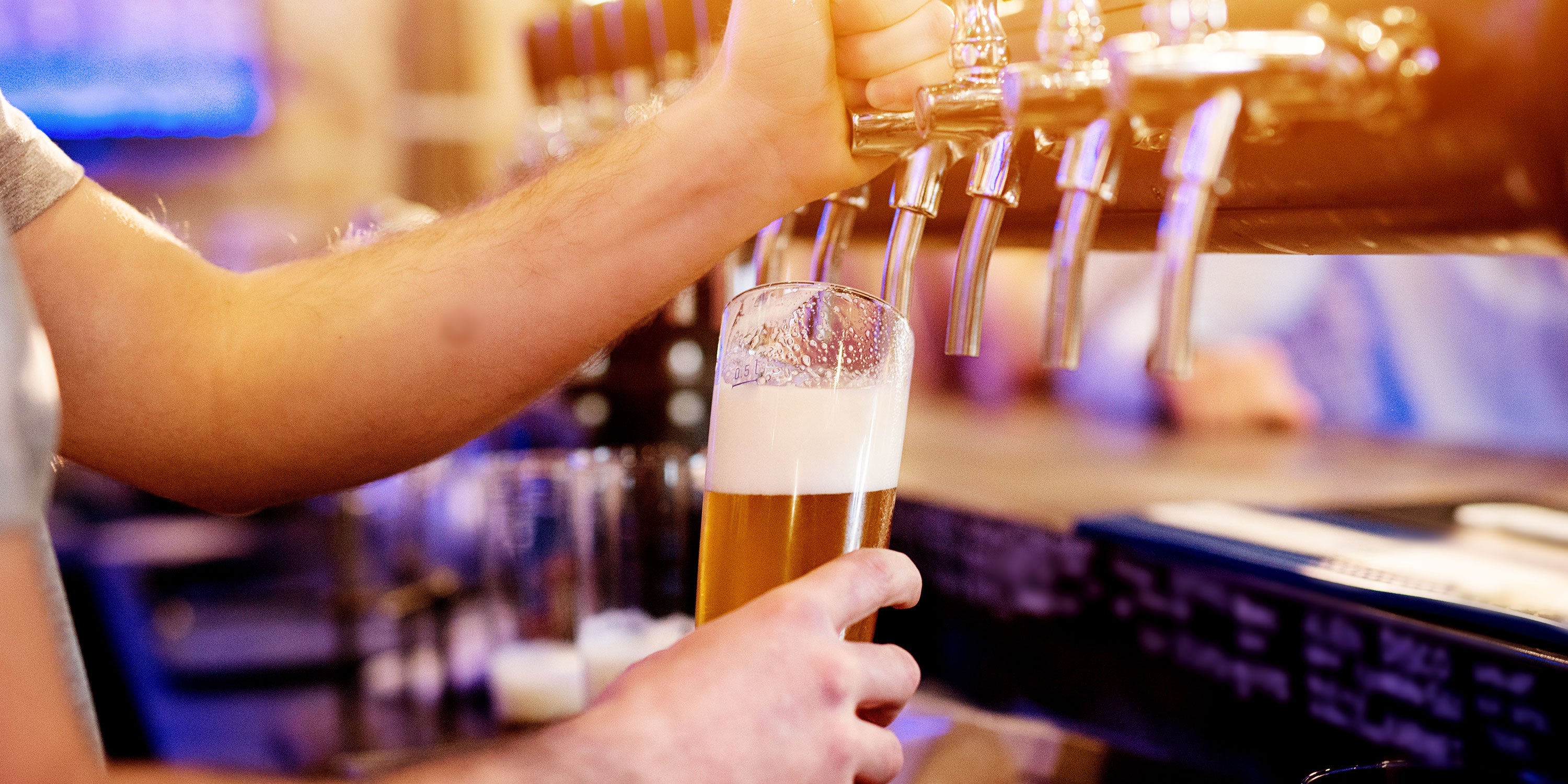 Photo of a bartender pouring a beer from a tap.