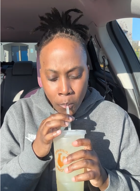 Popeyes pickle menu TikTok review showing a woman drinking the pickle lemonade in her care.