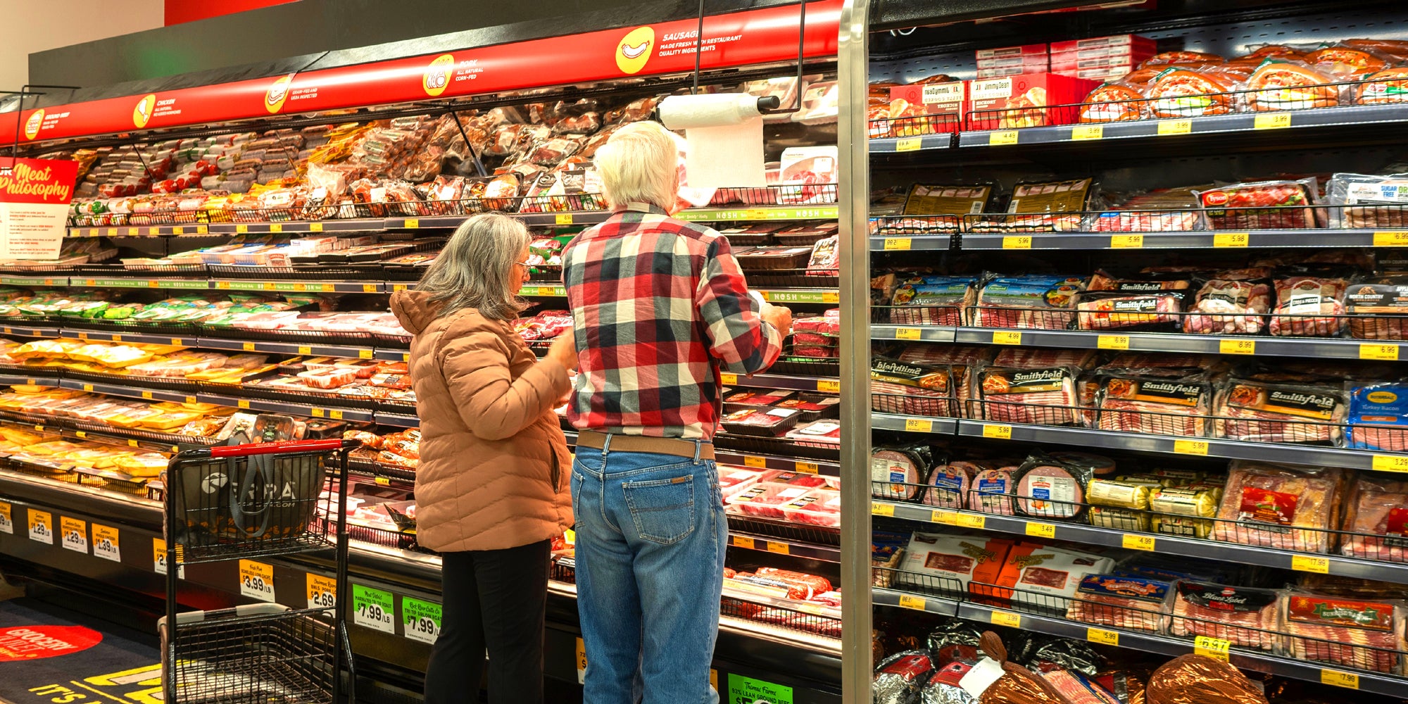 A couple shopping in the meat aisle.
