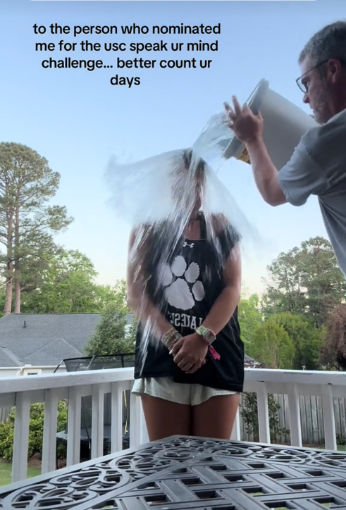 TikTok video of a woman getting splashed with a bucket of water on a deck with a caption reading 'to the person who nominated me for the usc speak your mind challenge... better count your days.'