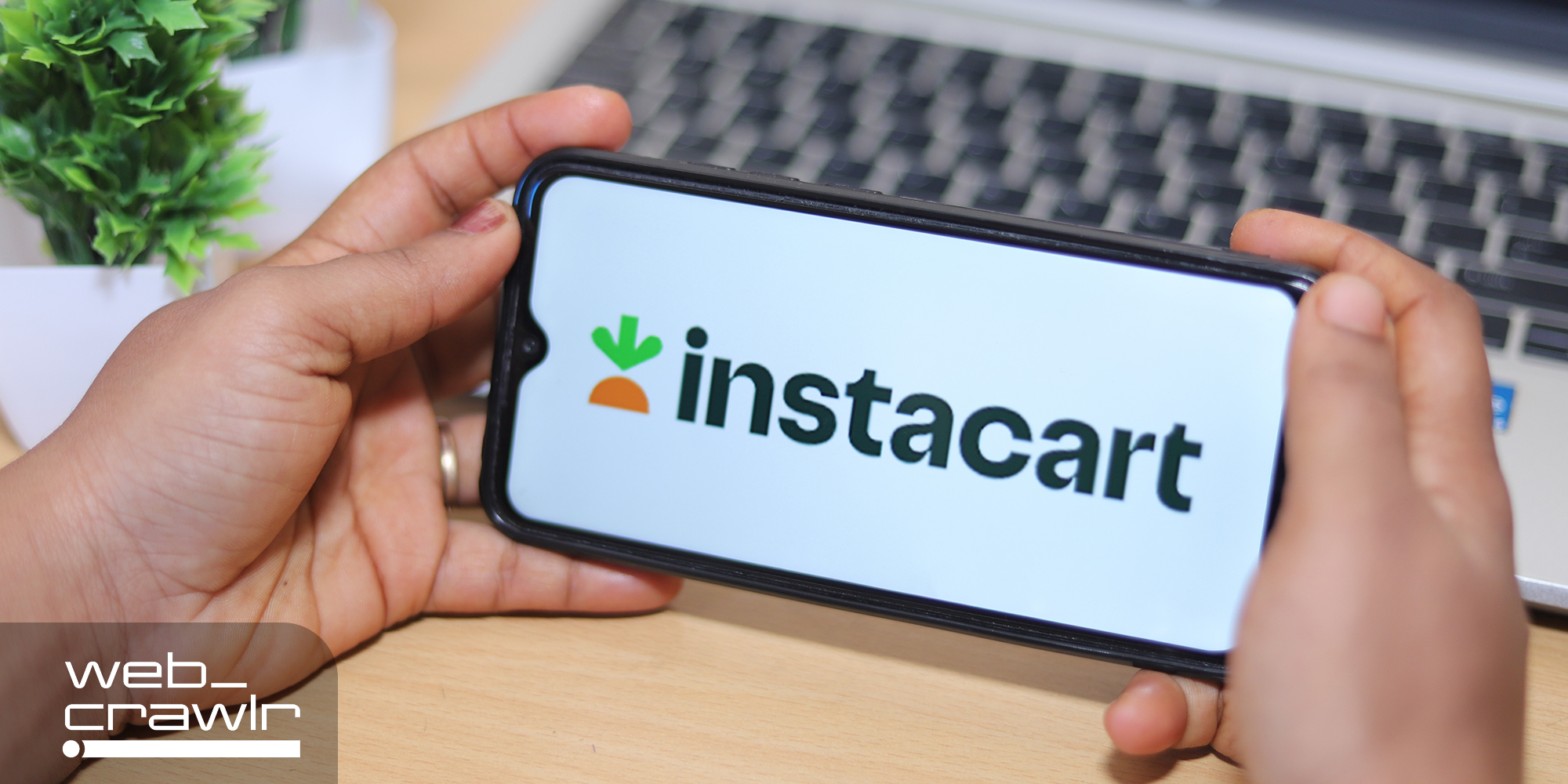 A phone with the Instacart logo on it. The Daily Dot newsletter web_crawlr logo is in the bottom left corner.