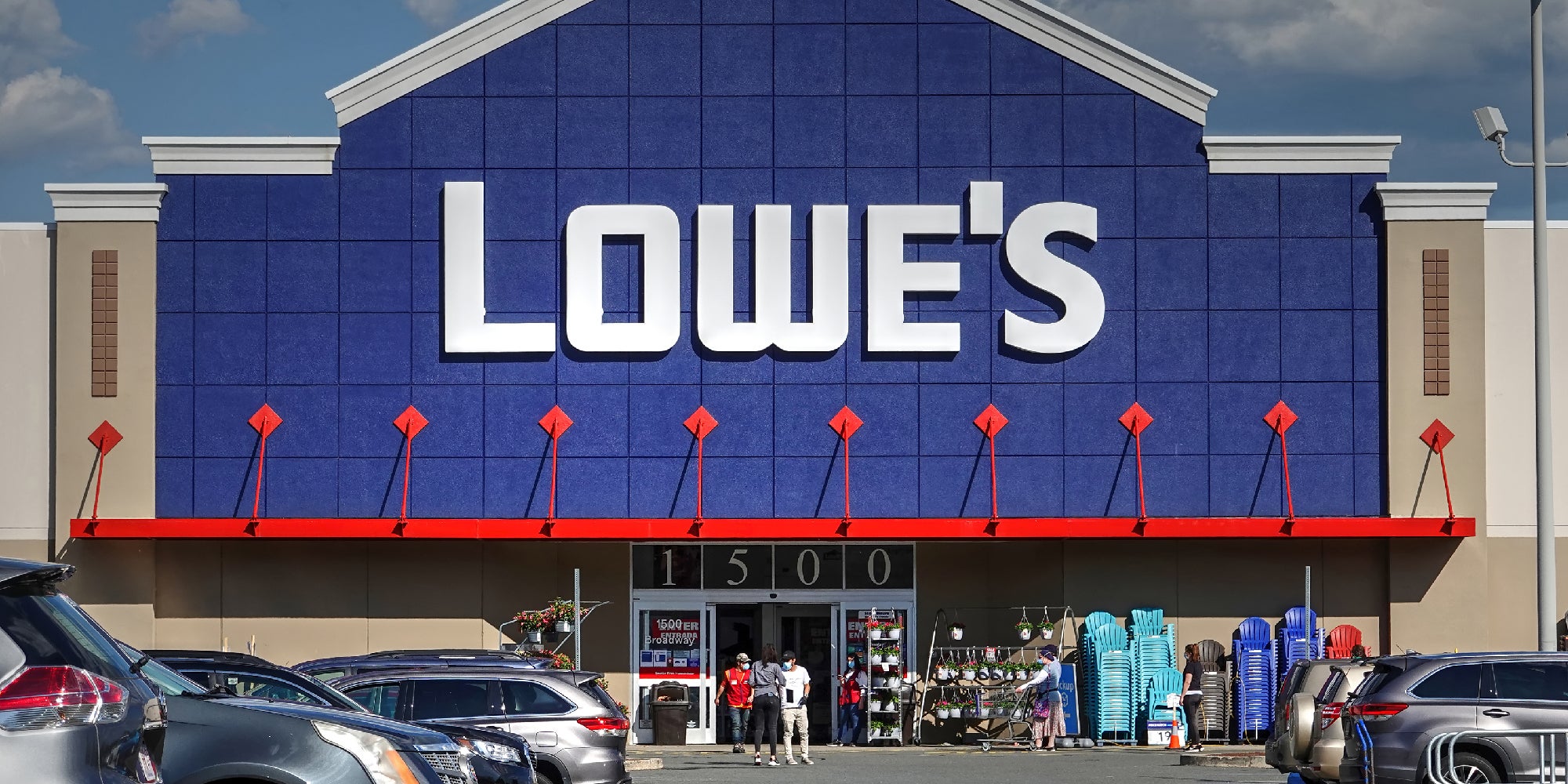 The exterior of a Lowe's store as customers walk in and out to the crowded parking lot.