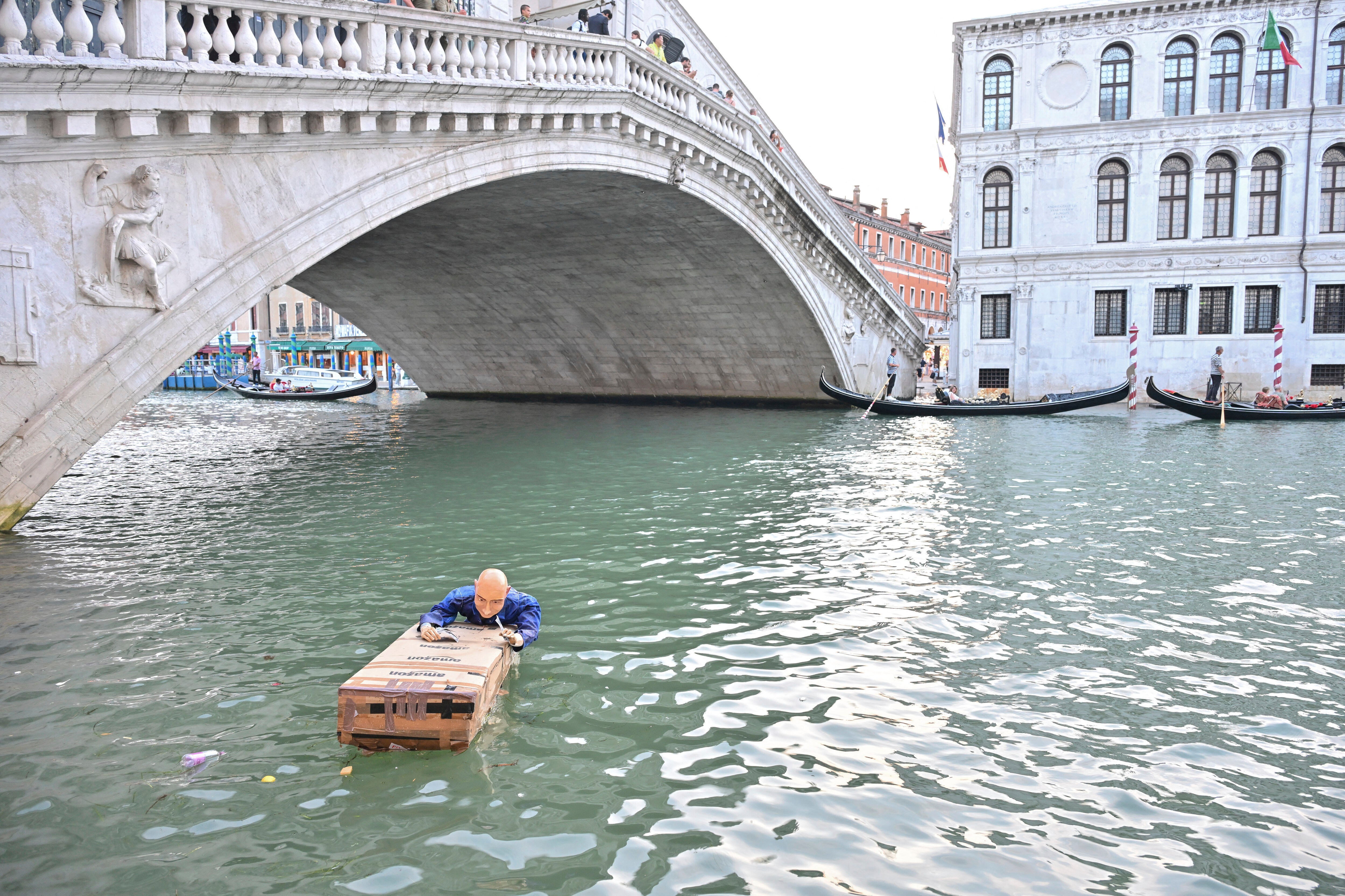 jeff bezos dummy floating in venice canal holding on to amazon boxes