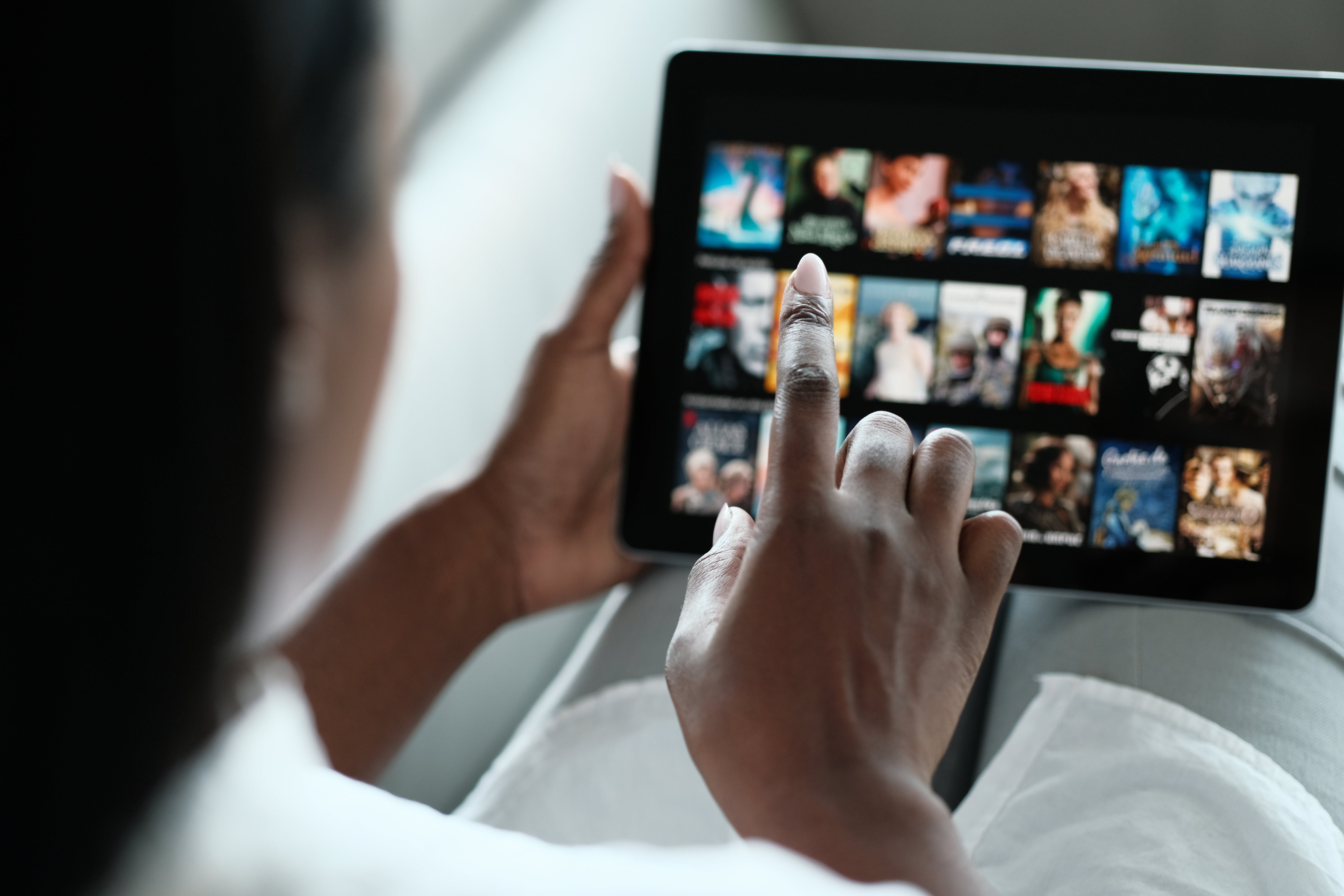 A woman scrolls through Netflix on a tablet.
