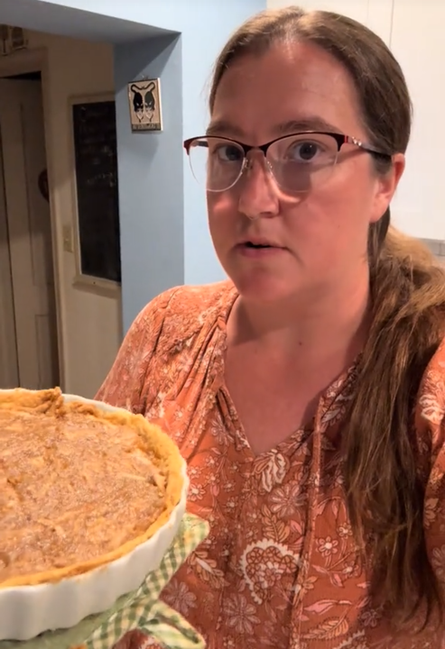 TikTok video showing a woman holding a pie and looking fearfully into the camera.