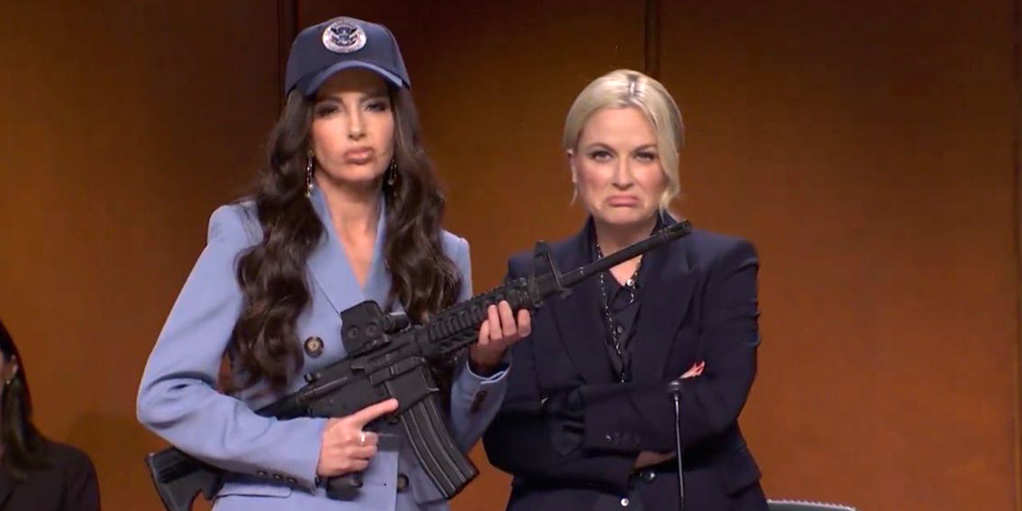 Tina Fey and Amy Poehler on October 11, 2025 episode of 'Saturday Night Live.' Fey is holding an automatic weapon, parodying Kristi Noem, and Amy Poehler is parodying Attorney General Pam Bondi.