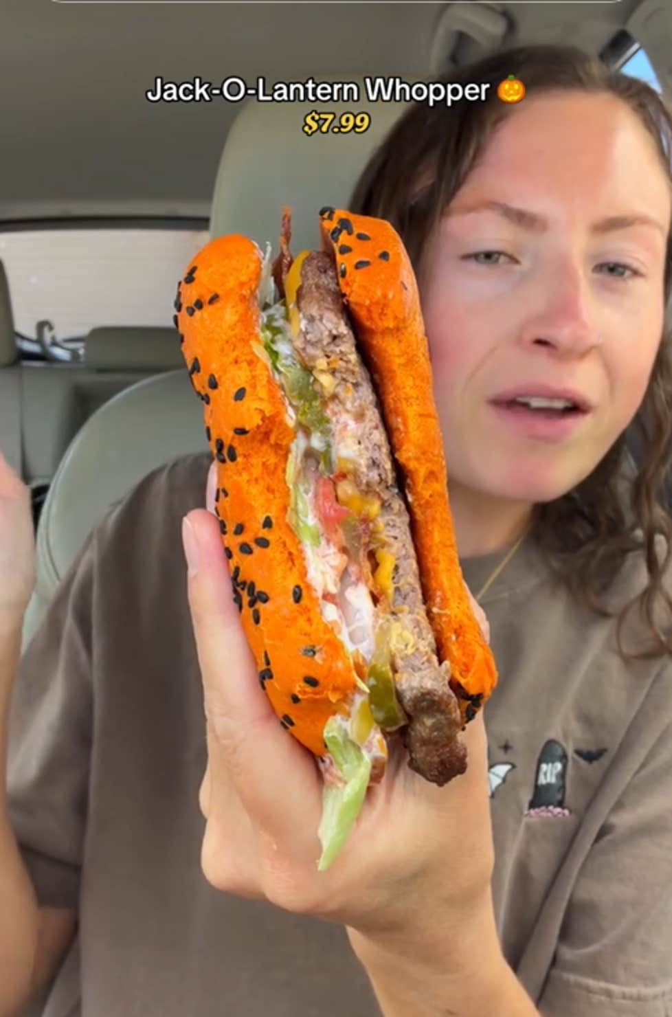 TikTok video of a woman in her car holding up a partially eaten Jack-O-Lantern Whopper.