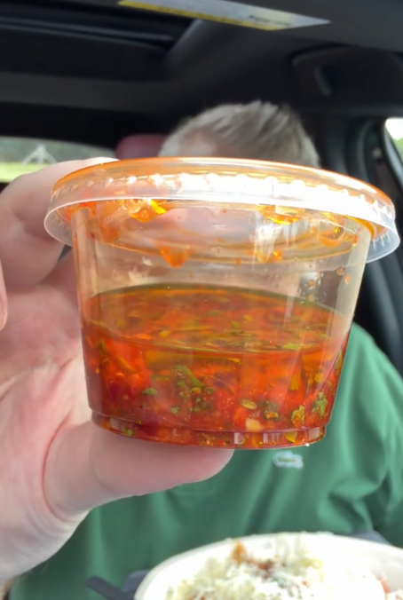TikTok video of a man showing a close-up shot of Chipotle's Red Chimichurri sauce.