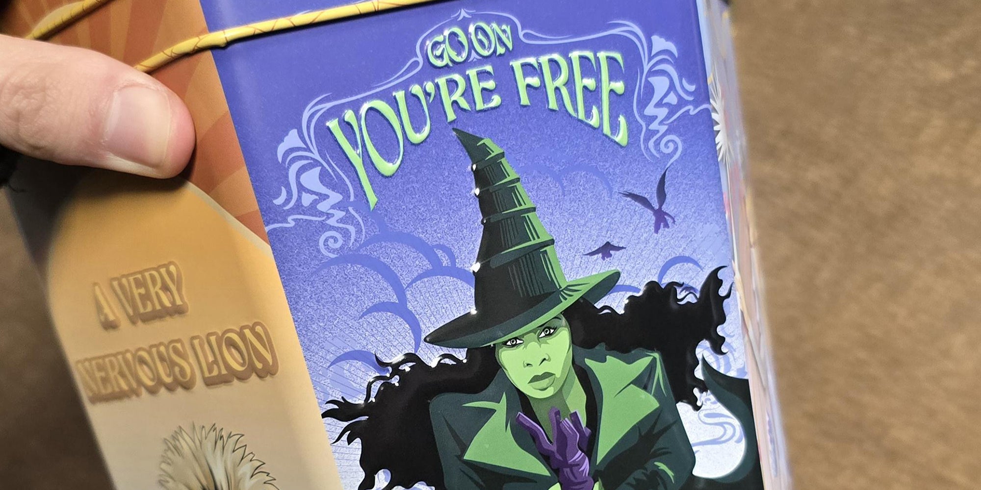 Hand holding new 'Wicked' movie theater cup that reads 'Go on you're free.'