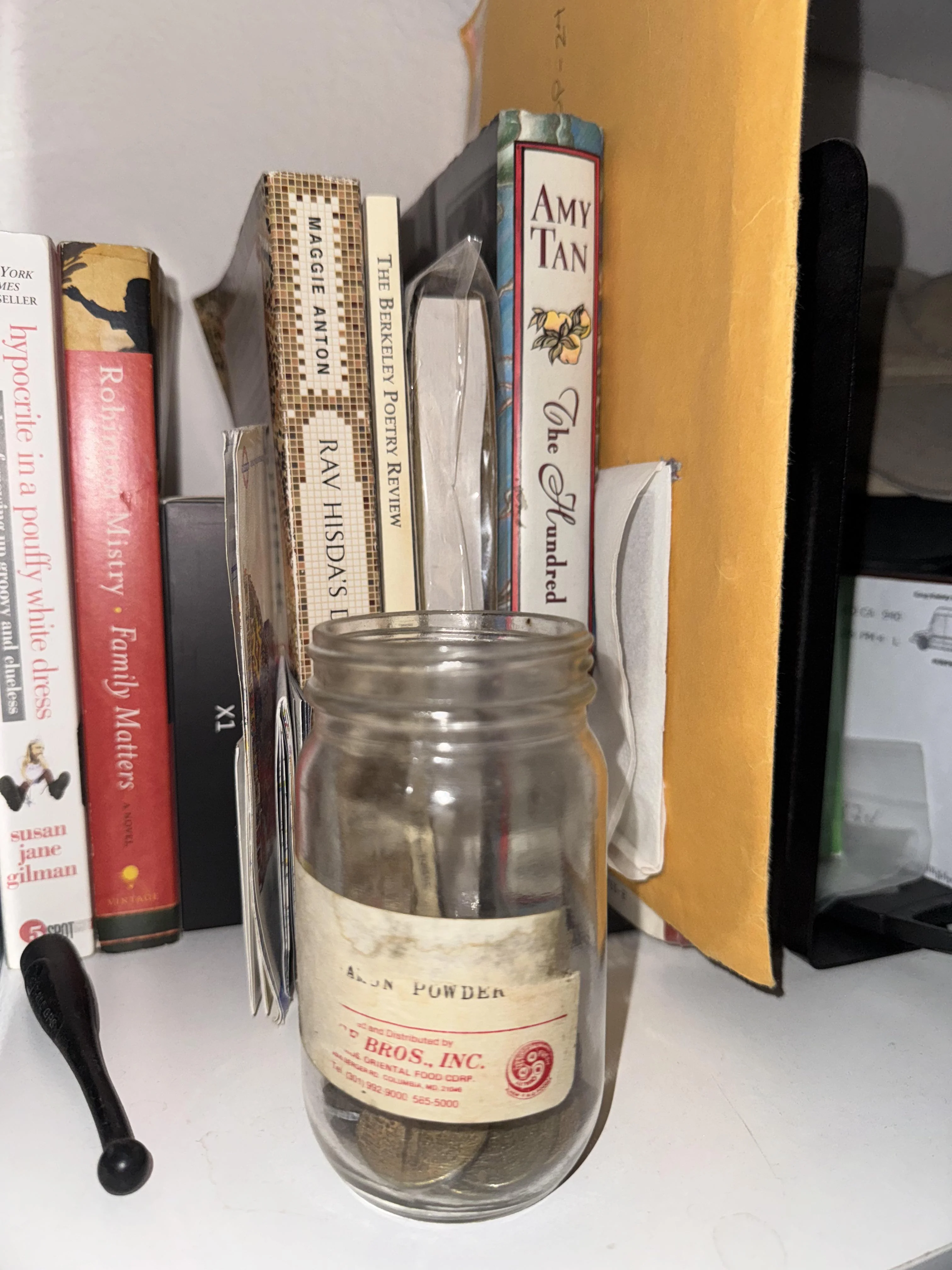 Photo of a jar of coins sitting on a white bookshelf.