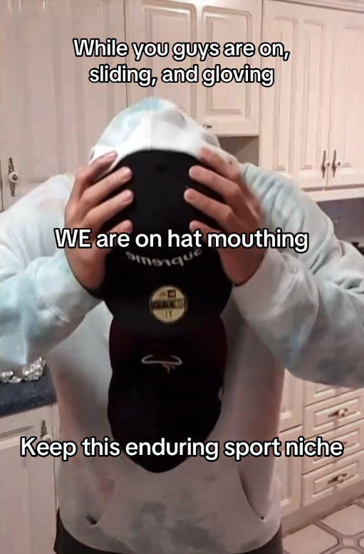 TikTok video of someone holding a hat with their mouth with a caption reading 'While you guys are on sliding and gloving, WE are on hat mouthing. Keep this enduring sport niche.'