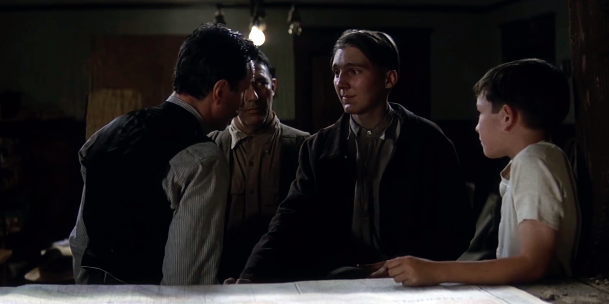 A dark scene from There Will Be Blood, Paul Dano in the middle looking earnest.
