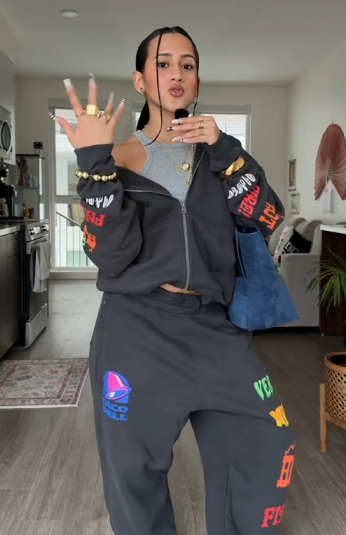 TikTok video with a woman speaking into a mic as she models the Taco Bell x Hollister collab hoodie and sweatpants.
