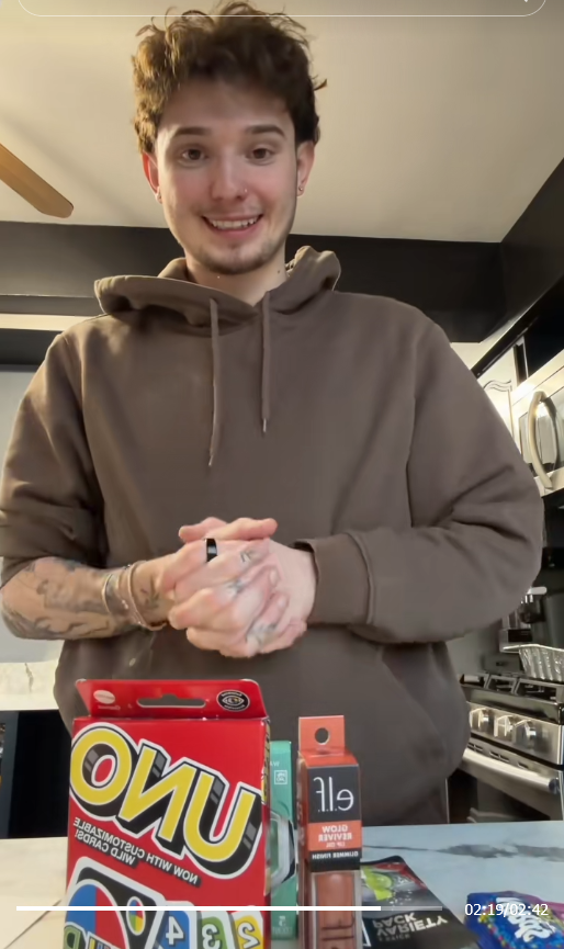 TikTok video of a man standing with a weak smile over a counter supporting five miscellaneous items from the Target Black Friday prize bag.