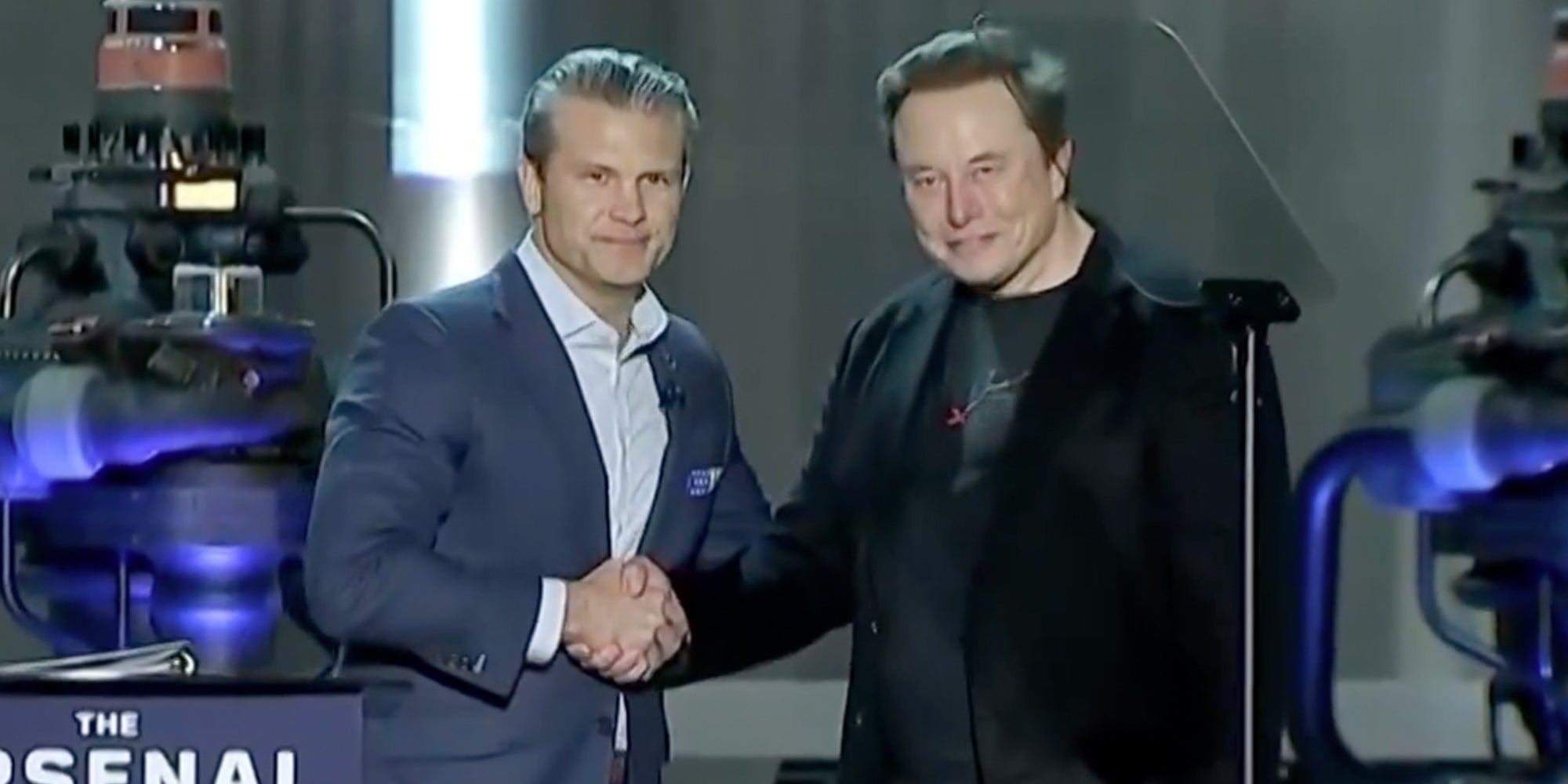 Defense Secretary Pete Hegseth shaking hands with Elon Musk onstage.