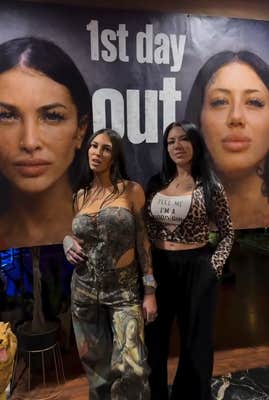 Two women standing under a banner with their mugshots reading "1st day out."