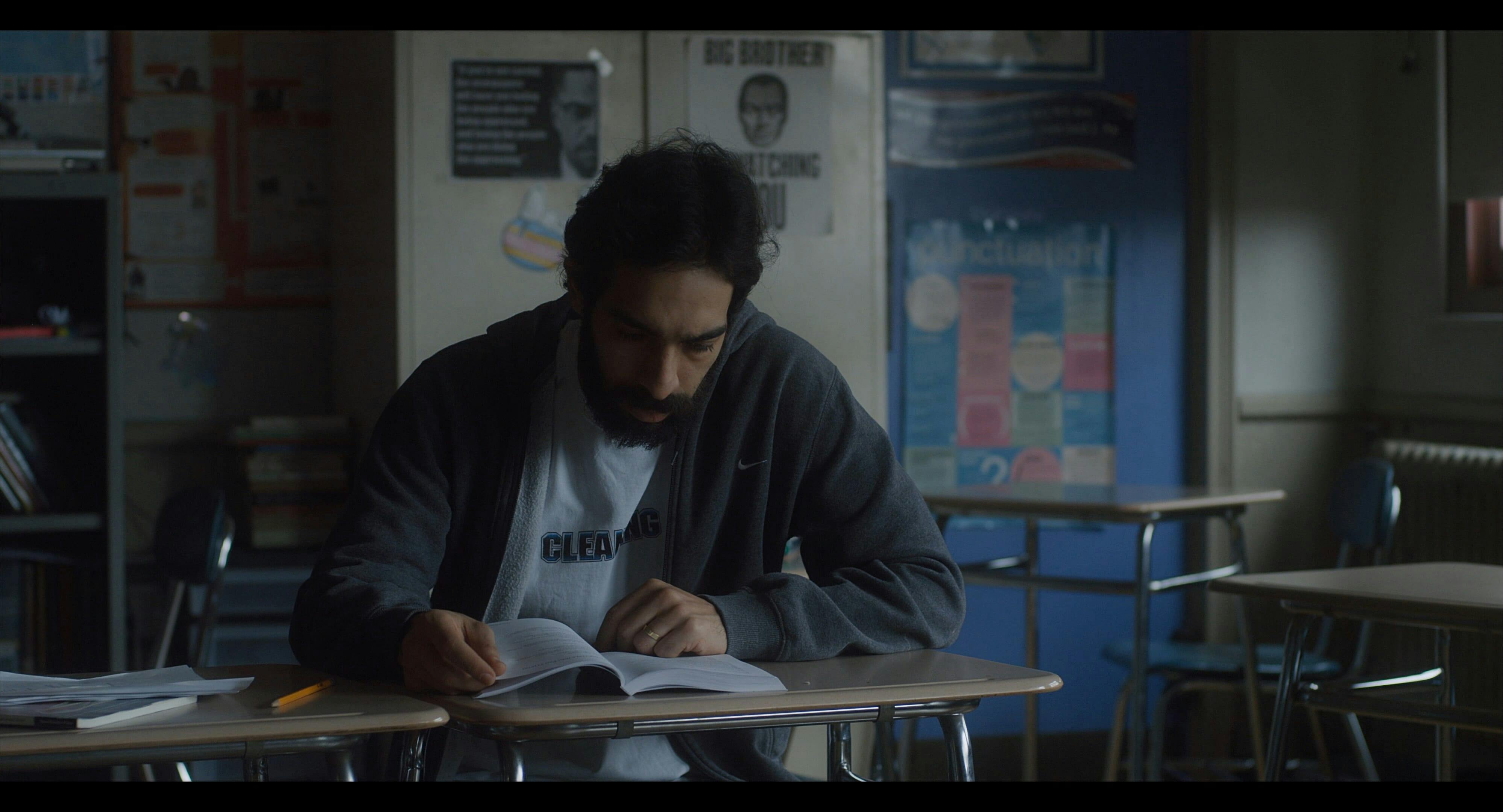 A man learns English in an empty, dark classroom in the film 'Carro.'