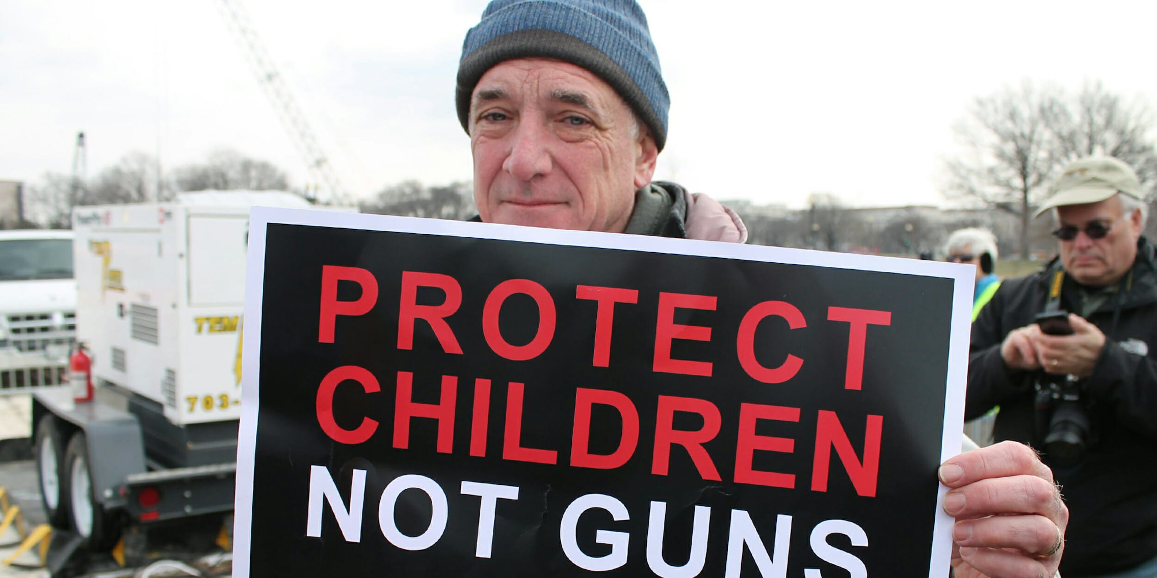 Man holding sign that says Protect Children Not Guns