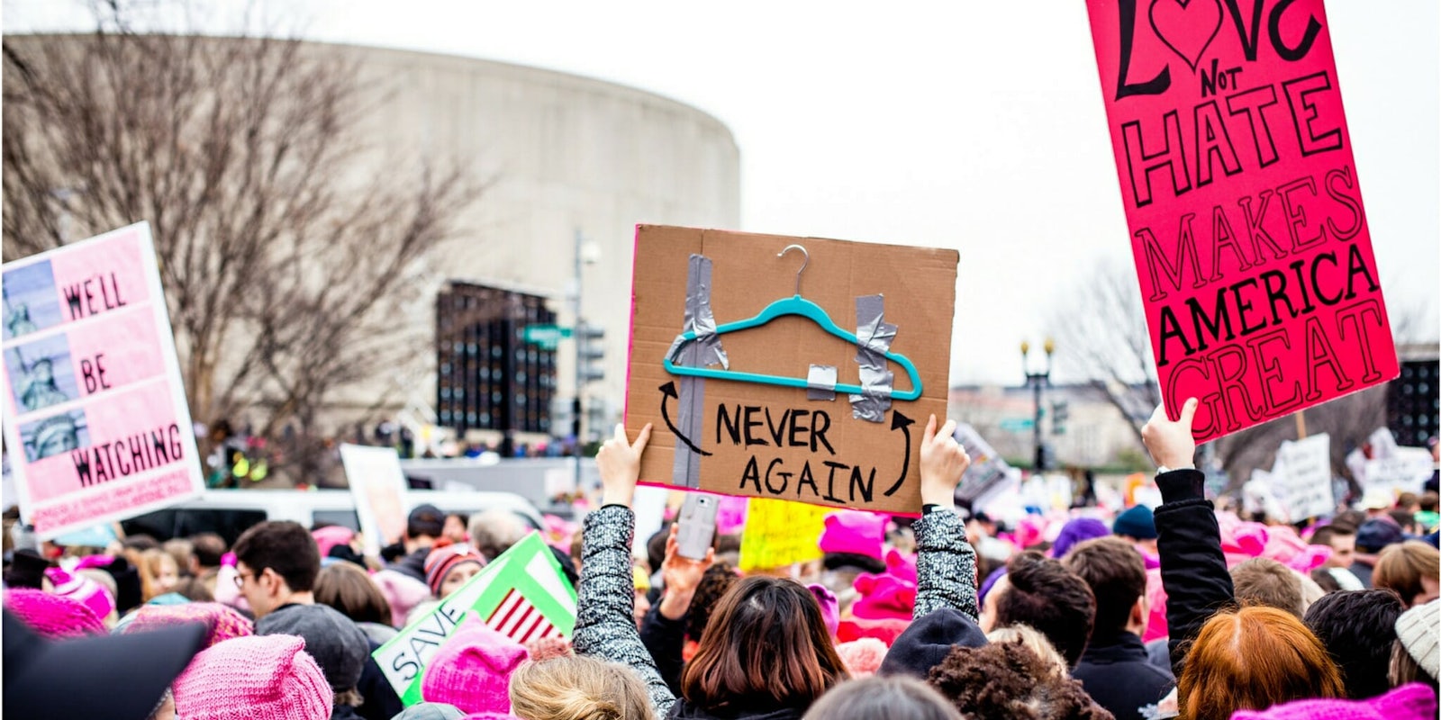 A sign from 2017's Women's March on Washington pointing to a hanger and saying 'Never Again.'