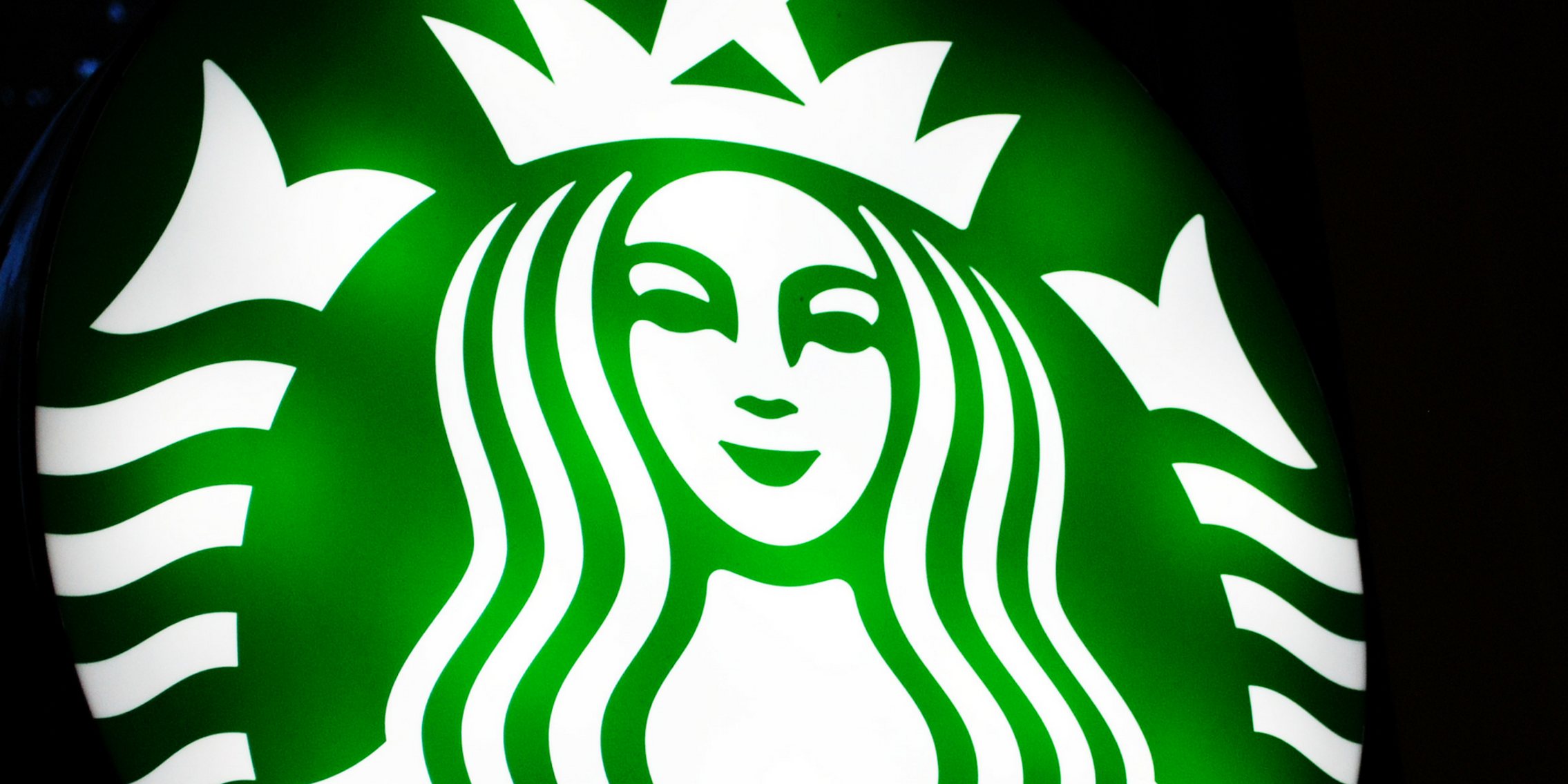 A lit sign with the Starbucks siren logo