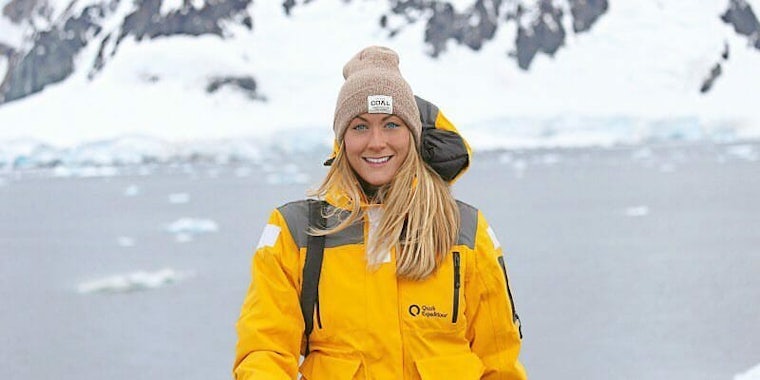 Cassie De Pecol, the first woman and fastest person to visit every country in the world, dressed in a yellow jacket and beanie near Paradise Island in Antarctica.
