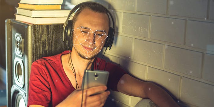 Man wearing headphones and using phone with facial recognition overlay