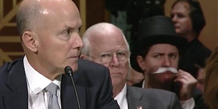 Person dressed as Uncle Moneybags Monopoly man watches Equifax Congressional hearing