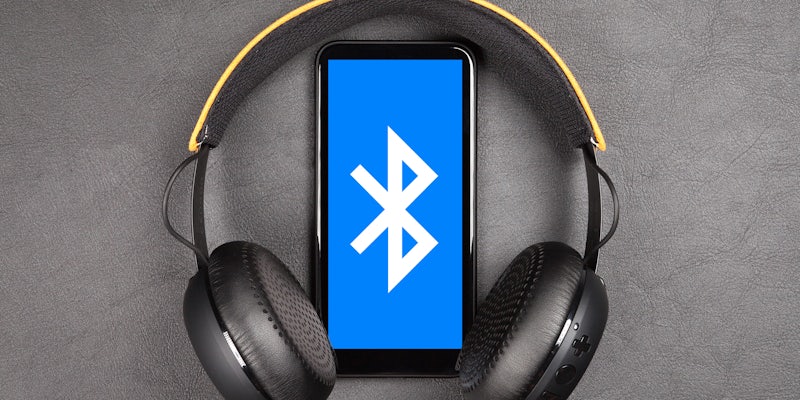 how does bluetooth work? Bluetooth logo on smartphone between wireless headphones