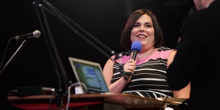 Shadi Petosky smiles holding a microphone while appearing on a podcast