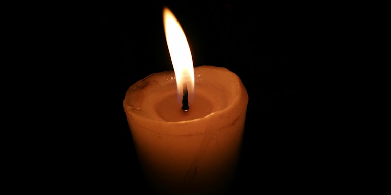 single lit candle on black background