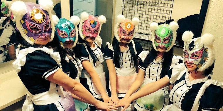 The band Virtual Currency girls stands in a circle with their masks on