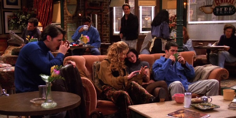Joey and Ross drink coffee in Central Perk, while Phoebe reads Monica's palm