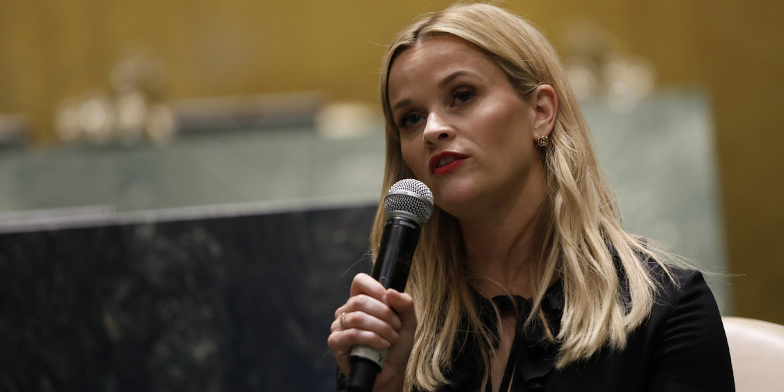 Reese Witherspoon holds a microphone while giving a speech at the UN