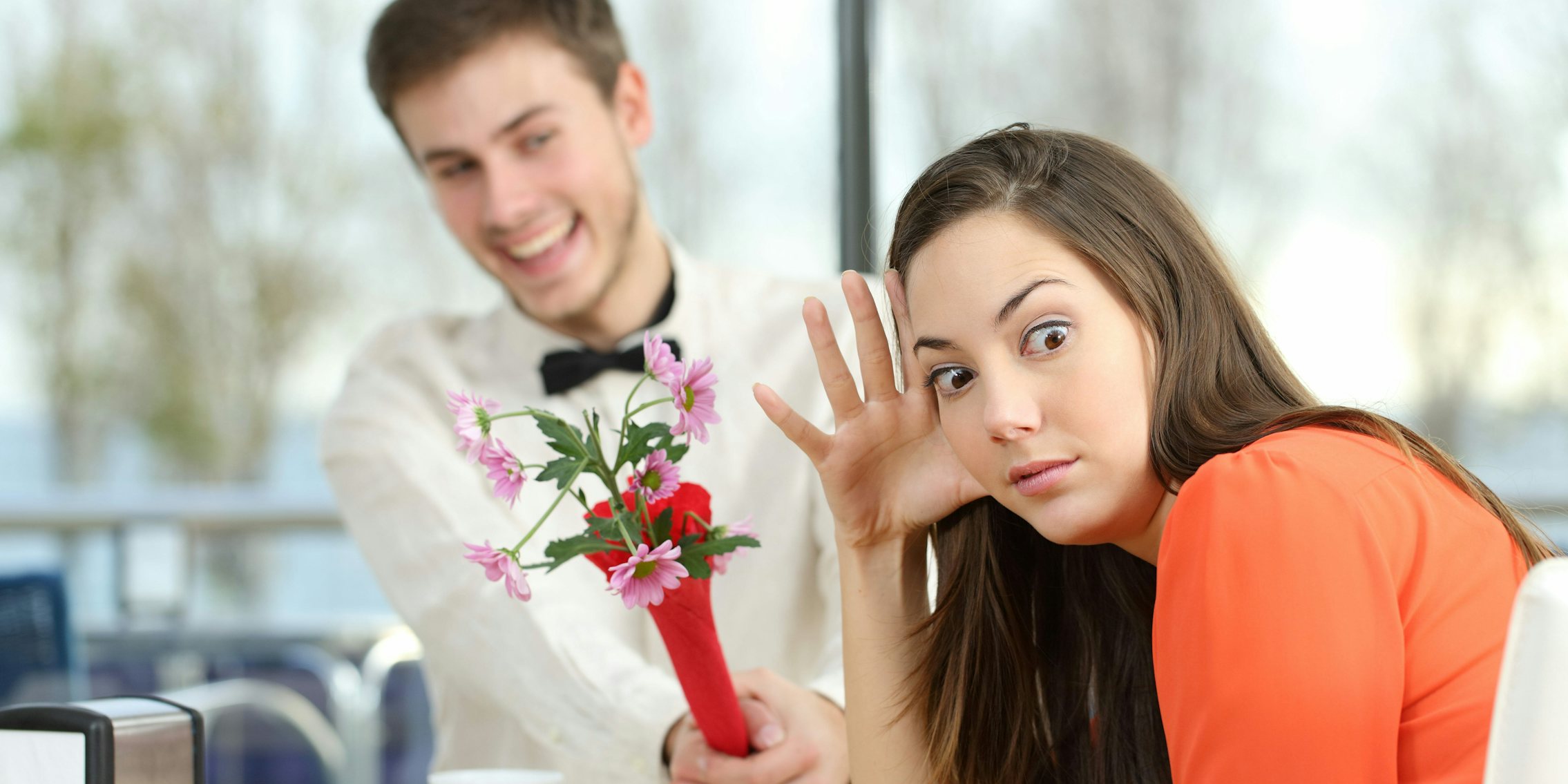 A woman rejecting a man giving her flowers.