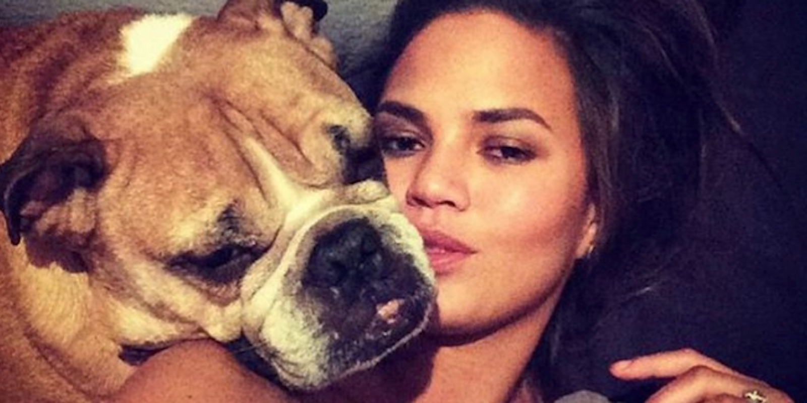 Chrissy Teigen lounges on a bed for a selfie with her English bulldog Puddy