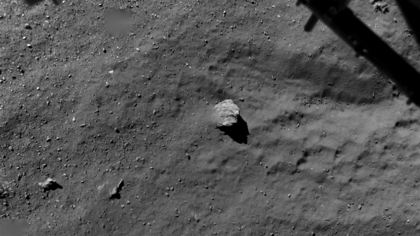 This image, acquired by the ROLIS camera, shows the comet Churyumov-Gerasimenko from an altitude of 67.4 metres on 12 November 2014. The camera, located on the bottom side of the lander, was able to photograph the originally planned landing site, Agilkia, during the descent. A portion of the landing gear is seen in the upper right corner of the image. Clearly visible is the comet's surface, exhibiting unexpectedly coarse material and a five-metre tall boulder. The ROLIS camera is operated under the scientific leadership of the German Aerospace Center (DLR)