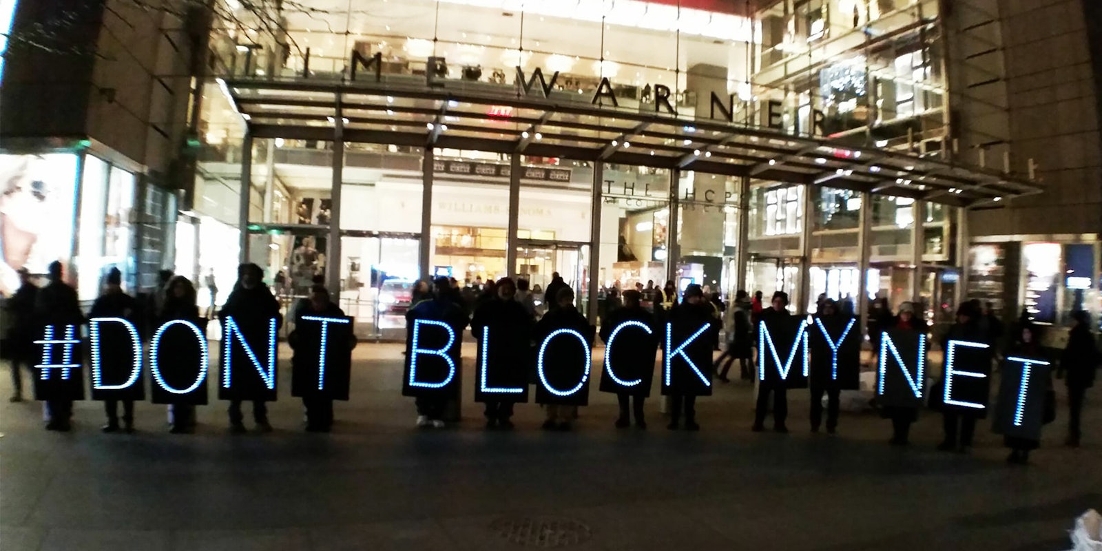 Protesters holding 'Don't Block My Net' lighted signs in front of Time Warner Cable building