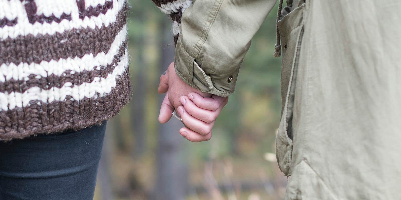 age of consent by state :A young couple holding hands while walking through the woods