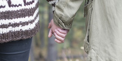 age of consent by state :A young couple holding hands while walking through the woods