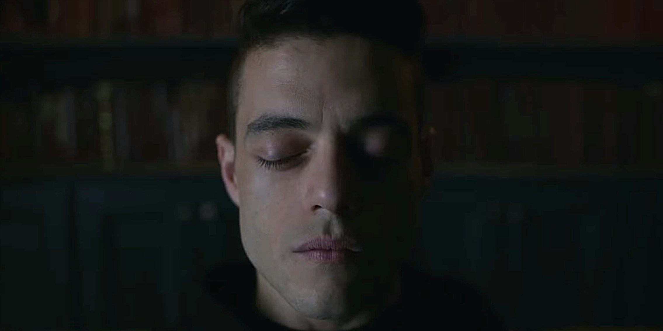 Rami Malek with his eyes closed in a dark room