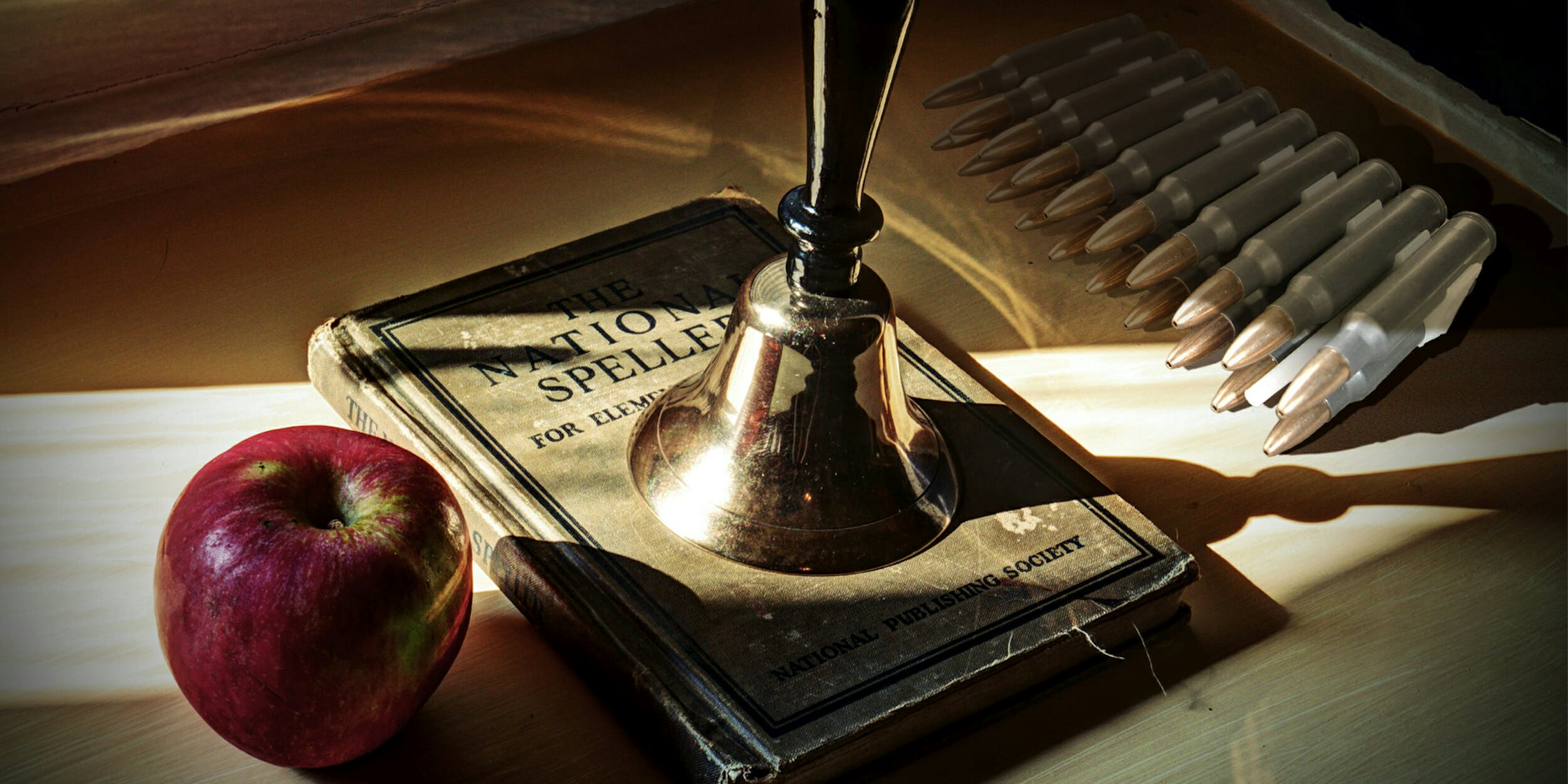 Teacher's desk with apple, spelling book, bell, and bullets