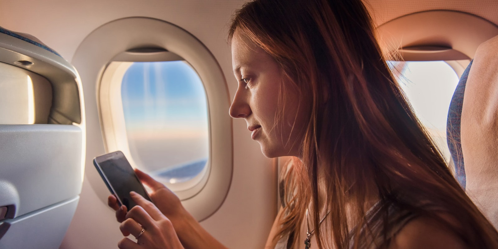 Woman Using Cellphone on a Plane