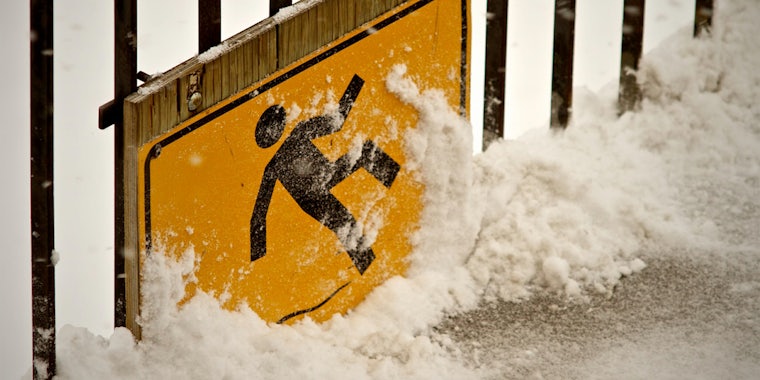Warning sign of man slipping on ice on snowy deck