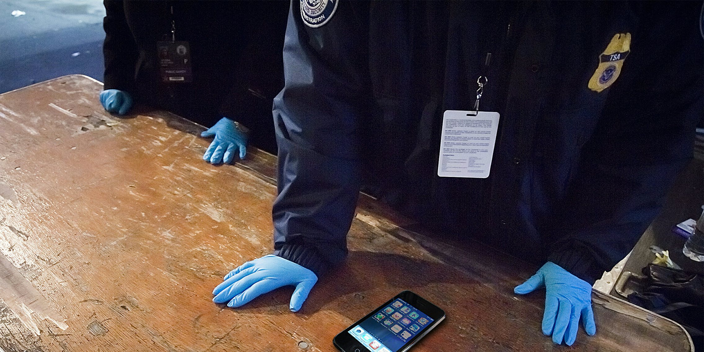 TSA screeners with blue gloves examine phone for social media accounts