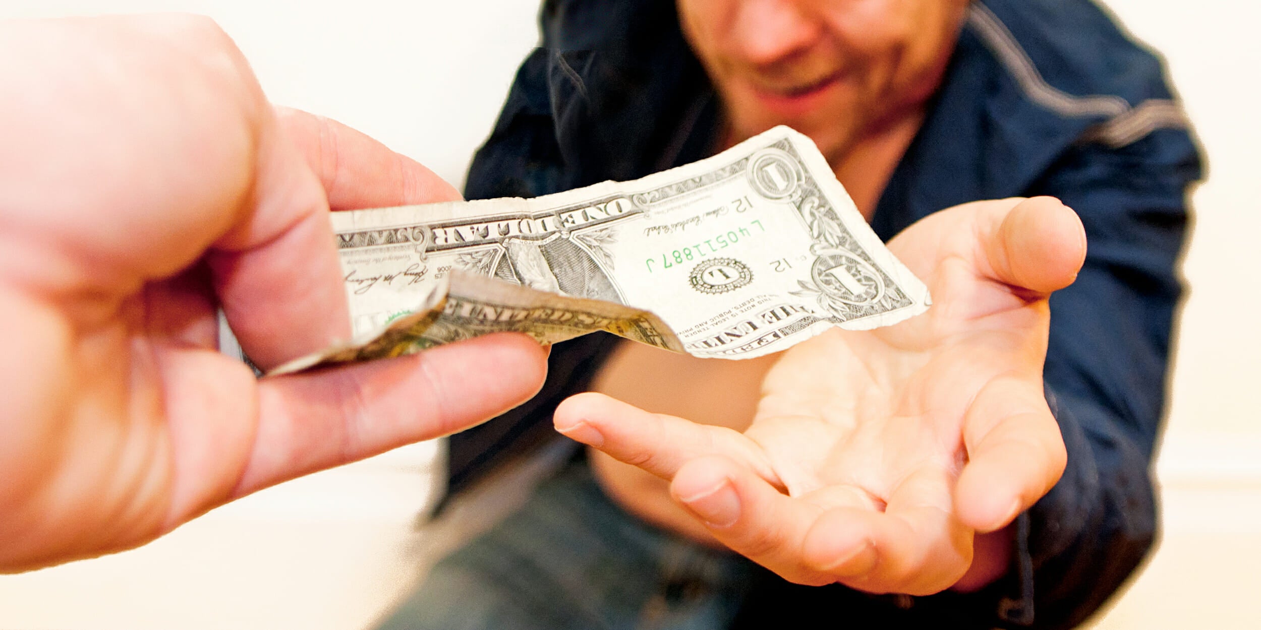 Person handing a dollar to a smiling man
