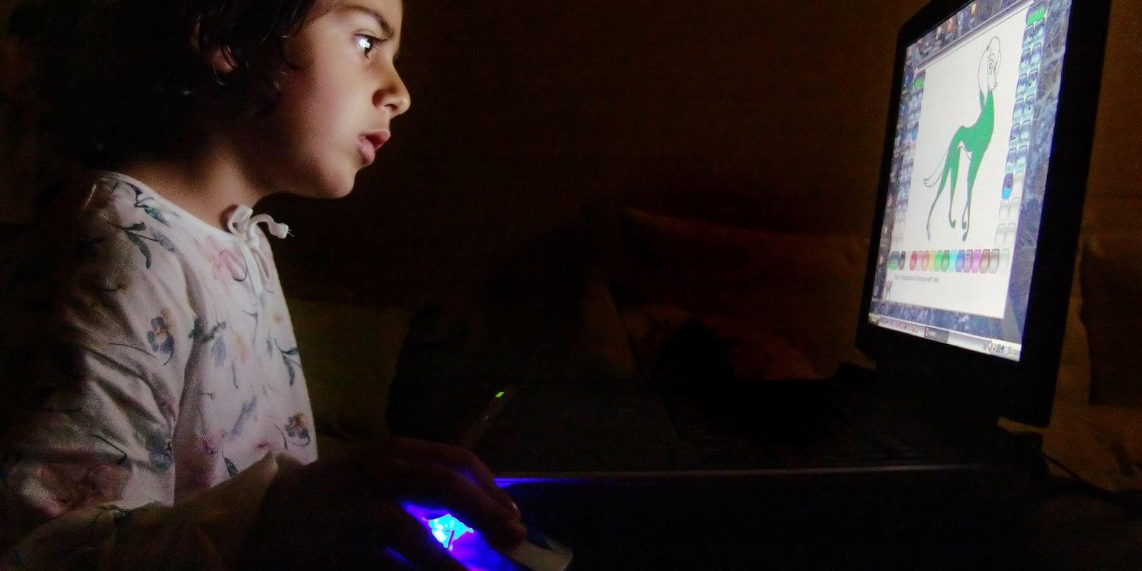 A teen using a computer in the dark