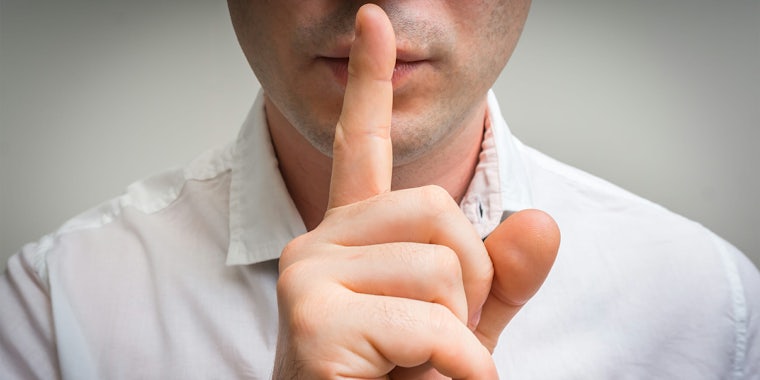 Man holding a finger up to his lips